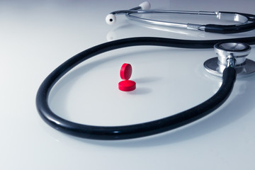 Doctor's Stethoscope snaking around red pills symbolizing emergency heart pressure