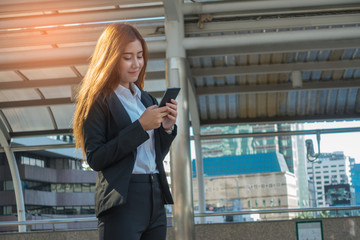 Young Asian businessman smiling while looking down at a cell pho