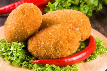 three fried breaded cutlet with lettuce on a cutting board