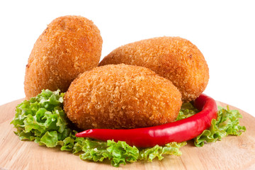 three fried breaded cutlet with lettuce on a cutting board isolated white background