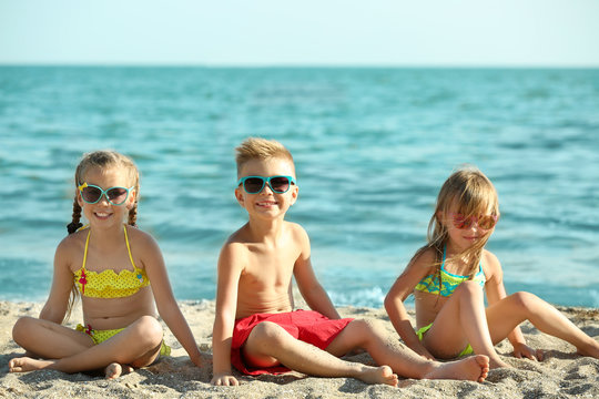 Cute kids sitting on beach sand