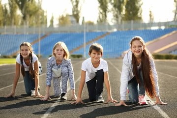 Cheerful children in ready position to run on track