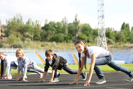 Cheerful children in ready position to run on track