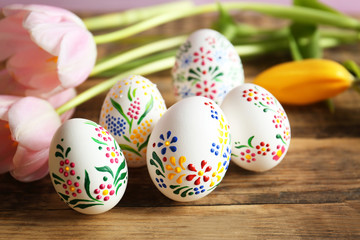 Fototapeta na wymiar Beautiful Easter eggs and flowers on wooden background, closeup