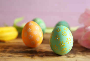 Beautiful Easter eggs with floral ornament on wooden table, closeup