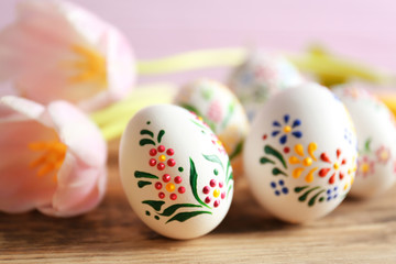 Beautiful Easter eggs and flowers on wooden background, closeup