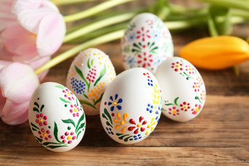 Beautiful Easter eggs and flowers on  wooden background, closeup