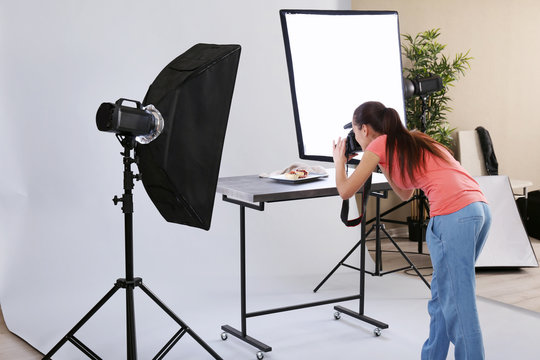 Young woman taking pictures of food in professional photo studio