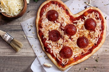 Heart shaped pizza ready to bake overhead view