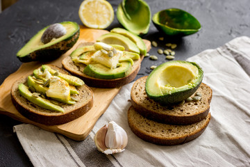 Obraz na płótnie Canvas making sandwiches with avocado healthy organic food top view