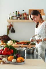 Young woman standing by the stove in the kitchen