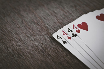 playing cards four fourcloseup on a wooden table. space for text. copyspace. game abstract and concept.