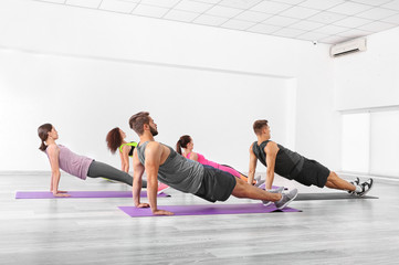 Fototapeta na wymiar Group of people doing yoga exercises in gym