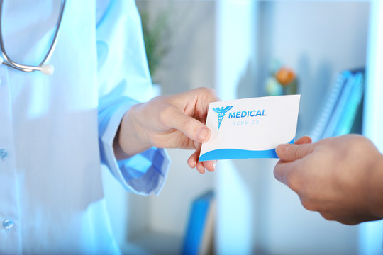 Medical service concept. Female doctor giving visiting card, closeup