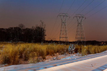 Industrial landscape - illuminated railway station by winter night with snowfall