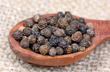 Black peppercorns in a wooden spoon