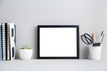 black frame, books and plant on shelf or table.