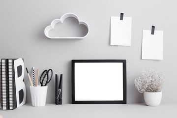 black frame on desk with two sticky notes, books and office supplies.