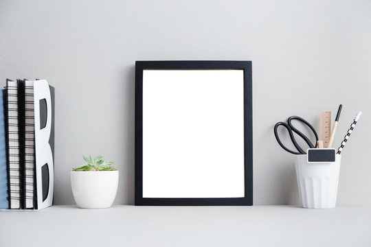 black frame, books and plant on shelf or table.
