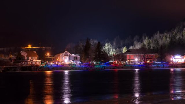 Time lapse of small town at night during the holidays with river in foreground