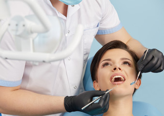 Young female patient visiting dentist office.Beautiful woman with healthy straight white teeth sitting at dental chair with open mouth during a dental procedure.Dental clinic.Stomatology.