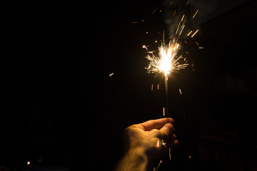 Hand holding a sparkler at night for Diwali Hindu Festival of lights in Mysore, Karnataka, India.