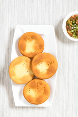 Traditional Chilean Sopaipilla fried pastries made of a bread-like leavened dough, served with Chilean pebre salsa, photographed overhead with natural light