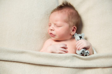 Newborn baby sleeps his tongue out on a light blanket