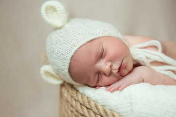 Newborn baby sleeps in a basket. Hat with ears