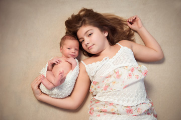 Newborn baby and his older sister lying on a blanket