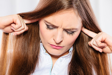 Fototapeta premium Stressed woman with closed eyes put fingers in ears,