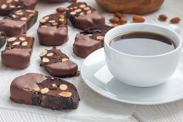 Homemade dark chocolate biscotti cookies with almonds, covered with melted chocolate, and cup of coffee, horizontal