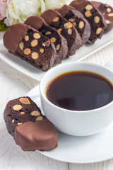 Homemade dark chocolate biscotti cookies with almonds, covered with melted chocolate, and cup of coffee, vertical