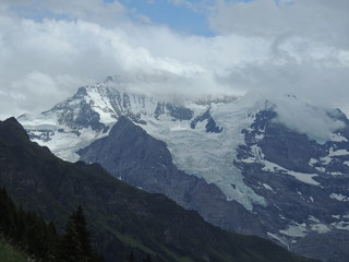 Fototapeta na wymiar Alpine glacier with mountain peak hidden in the clouds
