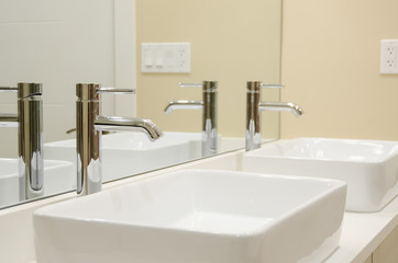 Two sinks in a bathroom with mirror wall and faucets