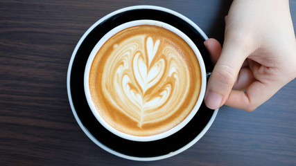 hands holding cup of coffee in coffee shop