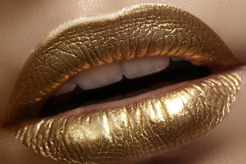 Beautiful closeup with female plump lips with gold color makeup. Fashion celebrate make-up, glitter cosmetic. Christmas style