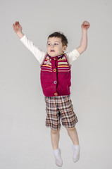 Little baby boy in plaid shorts and vest jumps
