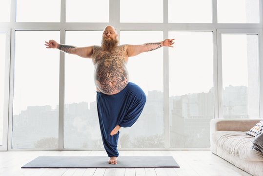 Tattooed man practicing yoga at home
