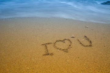 i love you written at the sand beach and on top soft wave. valentines day
