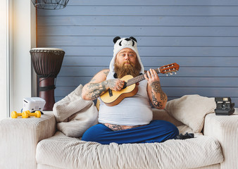 Man playing the guitar on his couch