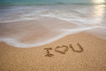 i love you written at the sand beach and on top soft wave. valentines day