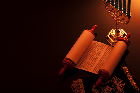 Religion and Judaism concept with candle lit scene of the holy Torah and a menorah with copy space