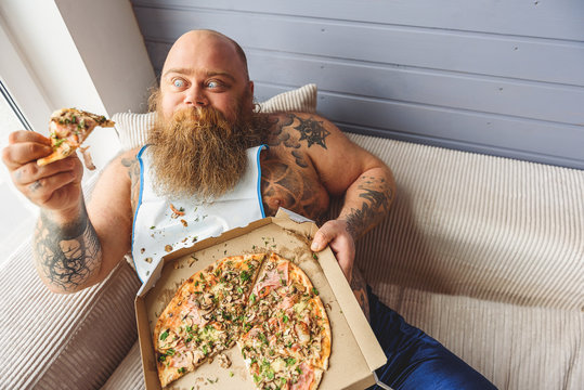 Man eating pizza on a couch