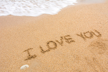 i love you written at the sand beach and on top soft wave. valentines day