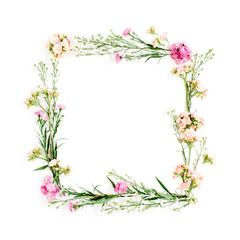 Obraz na płótnie Canvas Wreath frame made of pink and beige wildflowers, green leaves, branches on white background. Flat lay, top view. Valentine's background