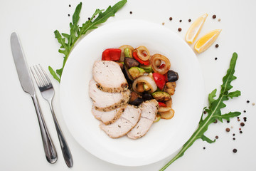 Baked chicken fillet with vegetable ragout. Tasty stewed vegetables with white poultry meat, served with knife and fork, flat lay. Healthy food, culinary, restaurant menu concept