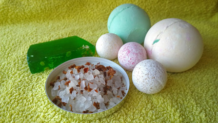 Toiletries bath soap, bath salt and bath bombs of different sizes on a yellow towel