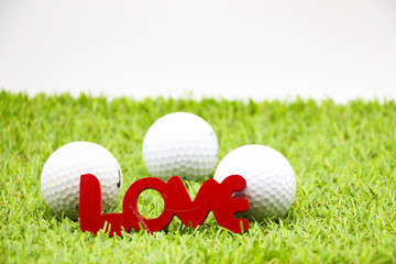 love letter with three golf balls are on green grass