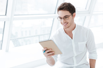 Handsome man holding tablet computer over big white window